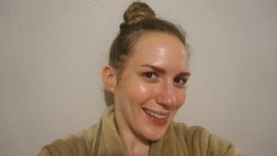 Woman wearing bathrobe smiling into camera